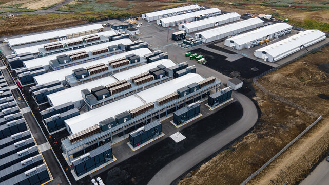 Aerial view of a large data center facility with rows of server buildings, cooling units, and paved access roads in Keflavik, Reykjanesbaer, Iceland.