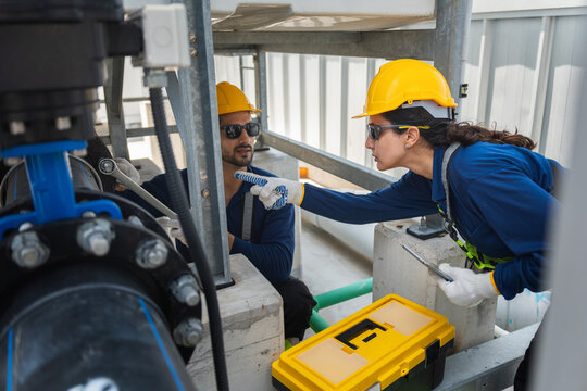 Professional engineers repairing industrial water pipe system with tools, Industrial maintenance team inspecting pipeline equipment with tablet and wrench