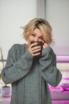 Blonde woman in a knitted sweater indoor portrait