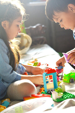 Adorable little siblings playing with building blocks.