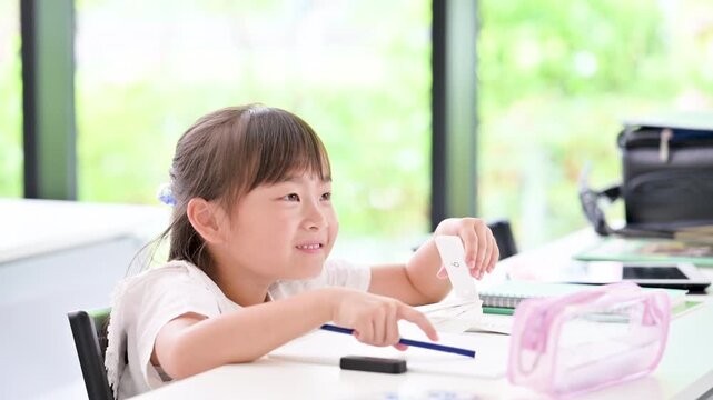 新緑が綺麗な教室で笑顔で勉強に取り組む、小学生、幼稚園位の笑顔の女の子・塾や学校、受験や自主学習のイメージの動画