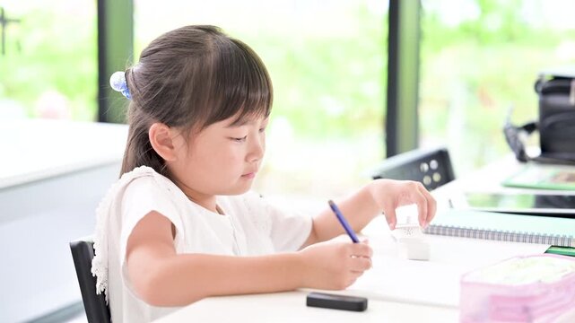 新緑が綺麗な教室で計算ドリルに集中して取り組む小学生位の女の子・塾や学校、受験や自主学習のイメージの動画