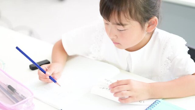 教室で計算ドリルに集中して取り組む幼稚園・小学生位の女の子・塾や学校、受験や勉強、学習のイメージの動画