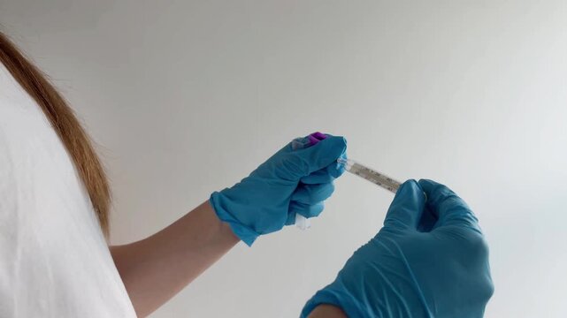 Medical professional wearing blue latex gloves carefully handling a traditional mercury thermometer, checking the patient's body temperature to diagnose a fever or illness