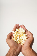 Obraz premium close up of hand holding popcorn on white background