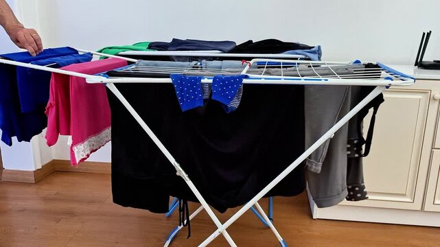 Drying freshly washed clothes on a foldable indoor laundry rack in a bright home. Everyday household routine showing efficient air drying, clean garments, and practical space-saving living