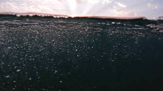Underwater part and sunset skylight splitted by waterline, underwater bubbles. Beautiful clouds and bright sun over sea water, Real image very suitable for backgrounds in Mediterranean sea, undersea.