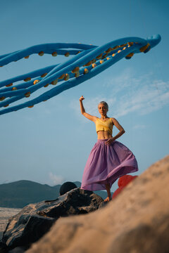 artistic woman posing near giant octopus kite at beach festival, creative summer scene with girl dancing by surreal inflatable sculpture by sea