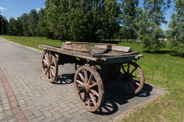 Obraz premium Vintage Wooden Cart Wagon On Pavement With Weathered Blue Planks In Sunny Countryside