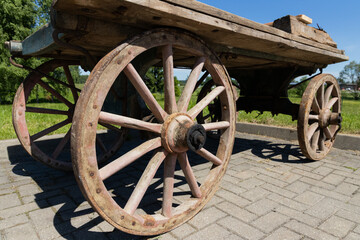 Obraz premium Rustic Vintage Wooden Cart With Iron-Rimmed Wheels On Park Pathway In Summer Sunlight