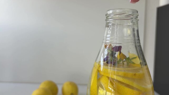 Woman's hand sealing a homemade floral lemonade glass bottle, promoting healthy lifestyle, natural ingredients, refreshing summer beverage and organic detox diet