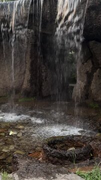 Water cascading over rocks into a serene pond creating a peaceful and relaxing natural soundscape with the soothing flow of a tranquil stream in a forest or park