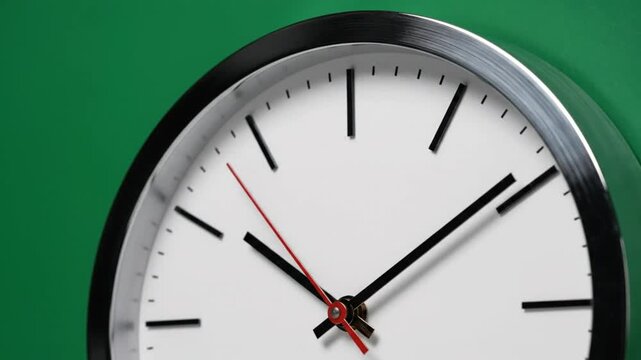 Close-up of Modern Wall Clock Face with Moving Hands against Green Background, Time Passing