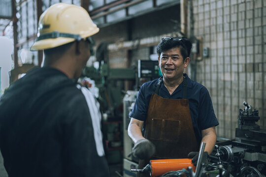 Close Up of Skilled Machinist Consulting with Customer in Industrial Machine Shop, Precision Engineering Service and Custom Metal Fabrication Workshop