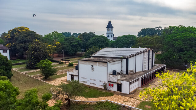 Aerial view of Achimota School featuring a prominent white building with solar panels, a historic clock tower in the background, and lush green trees in Achimota, Greater Accra Region, Ghana.