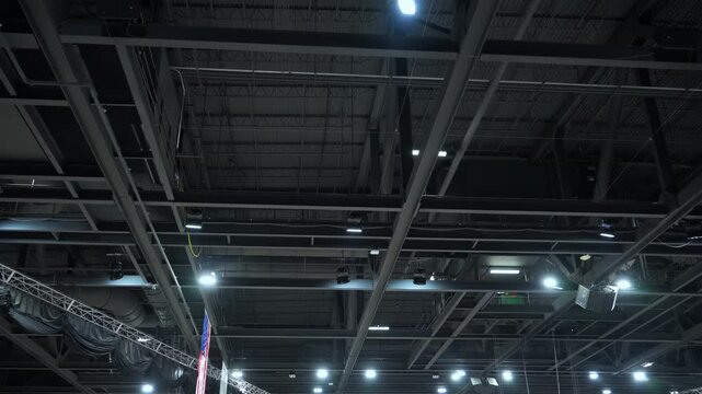 Metal roof trusses and ceiling structure inside a large hall or center. Industrial steel framework supporting lighting, ventilation, and event equipment. Wide view
