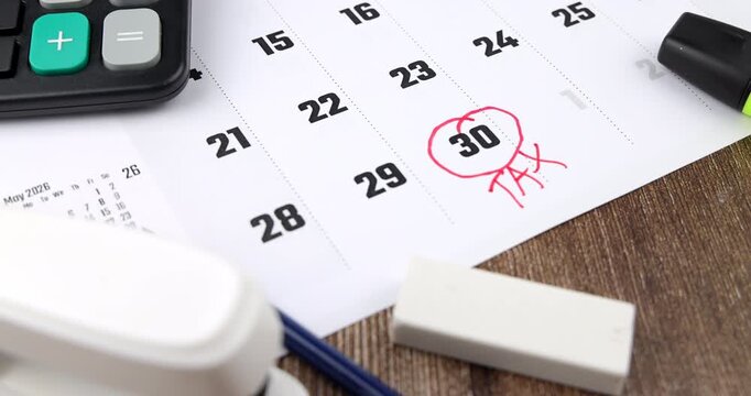 Widescreen camera pan over dark wooden table with business calendar displaying a red highlighted tax message and office calculator