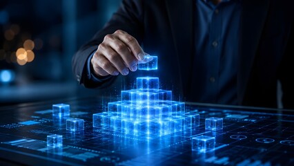 Obraz premium Digital business architecture and tech foundation concept with a hand building a glowing blue holographic cube pyramid
