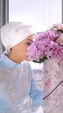 Beautiful muslim bride with make up in blue traditional dress for nikah sitting near the window