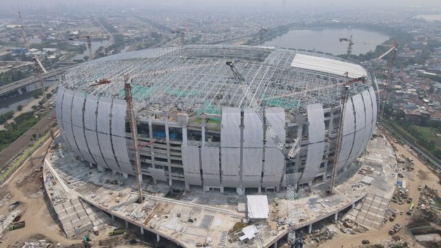 Aerial view of Jakarta International Stadium under construction with steel framework and surrounding cranes in Tanjung Priok, Jakarta, Indonesia.