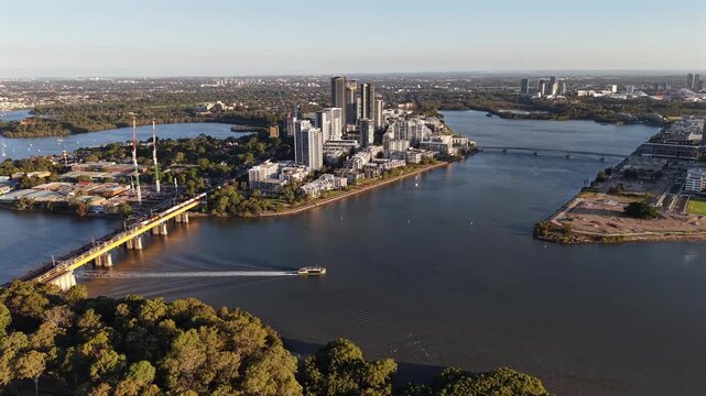 Aerial drone video panning left facing south over Rhodes in Sydney, capturing waterfront apartments, Parramatta River views, urban parkland, and modern residential living in Australia