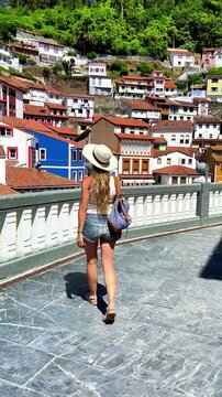 Tourist woman walking and looking at colorful houses of Cudillero village in Spain
