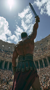 Roman gladiator warrior holding up a steel sword in victory inside a crowded ancient colosseum arena under the bright sun.