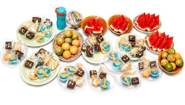 snack and fruit table arrangement featuring watermelon slices oranges brownies jelly cups and cookies isolated on white background