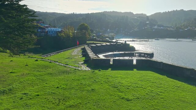 Panoramic aerial view of San Sebastian Castle in Corral, Valdivia, Chile, on a sunny day, showing a line of cannons flanked by stone fortifications