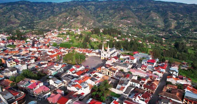 This cinematic aerial drone footage showcases the picturesque artisan town of Chordeleg, located in the Azuay province of Ecuador, captured during the afternoon. The wide shot highlights the layout of