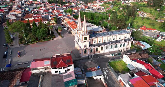 This cinematic aerial drone footage showcases the picturesque artisan town of Chordeleg, located in the Azuay province of Ecuador, captured during the afternoon. The wide shot highlights the layout of