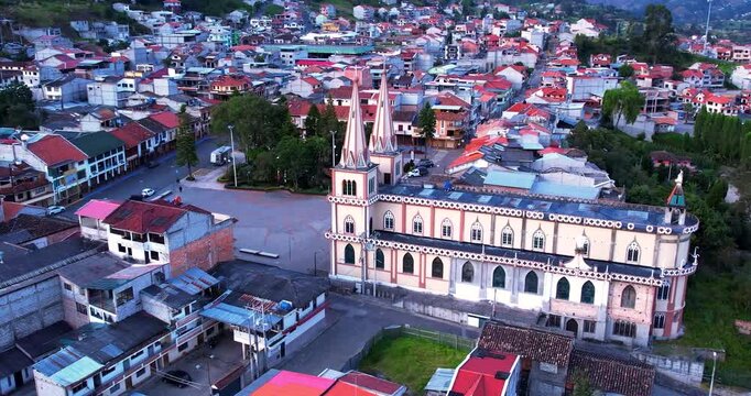 This cinematic aerial drone footage captures the beautiful central Catholic church of Chordeleg, a famous artisan town in the Azuay province of Ecuador, bathed in soft morning light. The video provide
