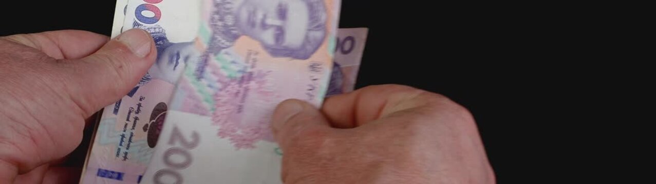Hands counting 200 ukrainian hryvnia banknotes symbolizing finance economy income and payment with currency.