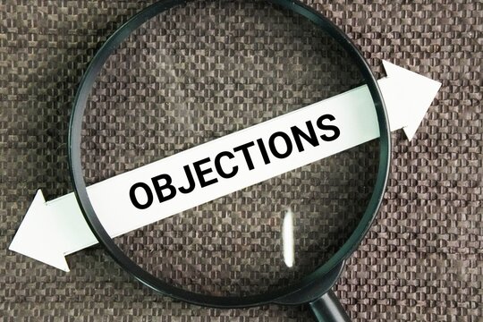 Magnifying glass with the word Objections. a reason or argument offered in disagreement, opposition, refusal, or disapproval
