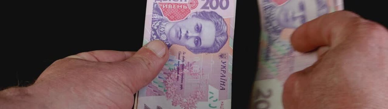 Human hands counting ukrainian hryvnia 200 uah banknotes Depicting financial transactions savings and economic concepts.