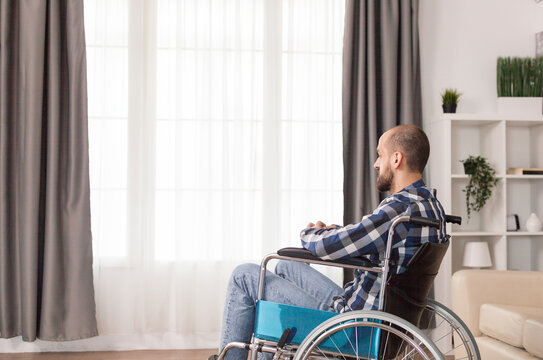 Disabled freelancer works on a laptop in a living room with a large display, showing remote work, accessibility and serious home office focus.