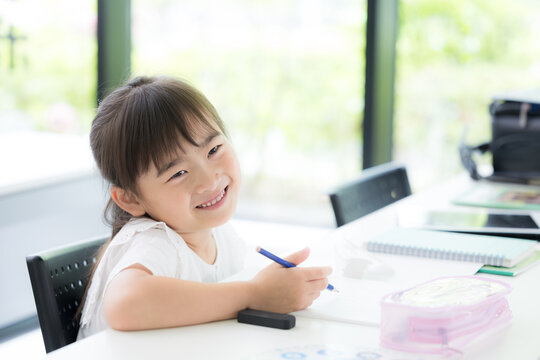 勉強に笑顔で取り組む幼稚園・小学生位の女の子・塾や学校、受験や勉強、学習の勉強がわかった！ポジティブイメージ