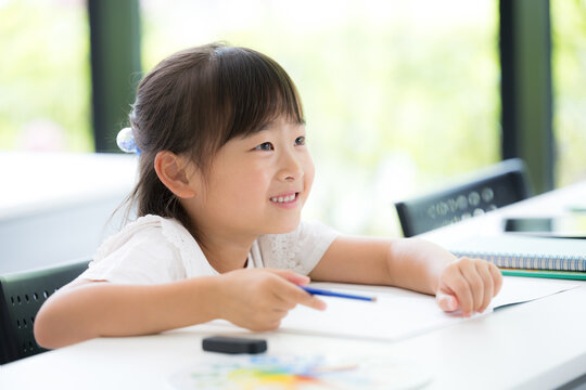 教室で黒板を見る勉強に集中して取り組む幼稚園・小学生位の女の子・塾や学校、受験や勉強、学習の勉強がわかった！ポジティブイメージ