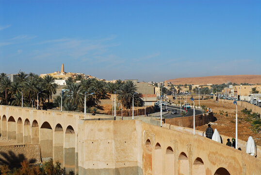 Algeria, Ghardaia, people walking on bridge with vehicles on the move on winding road