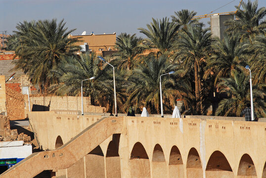 Algeria, Ghardaia, people walking on bridge with vehicles on the move on winding road