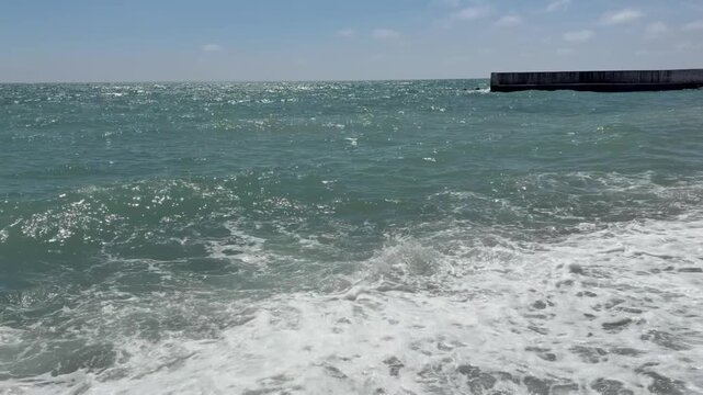 Whitecaps of sea waves wash the pebble shore on a bright sunny day. Summer, sea, relax