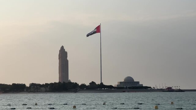 United Arab Emirates flag waving in the sky. Flag in the capital of UAE, Abu Dhabi. Flag of the UAE seen outdoors over the gulf in Dubai.