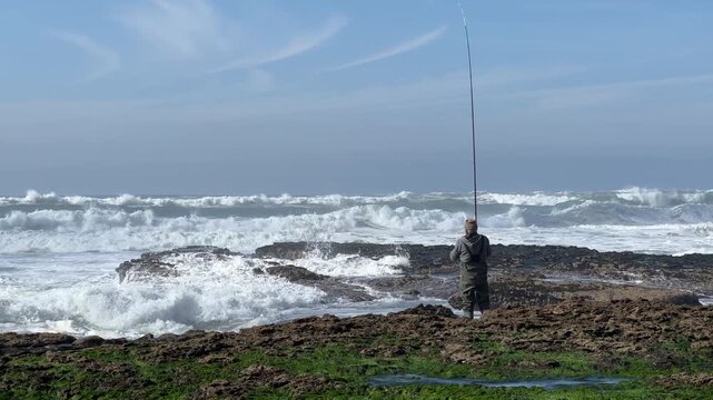 Fisherman fishing in the ocean. Rock fishing with powerful ocean waves. Beautiful video of a man surf fishing from the ocean coastline.