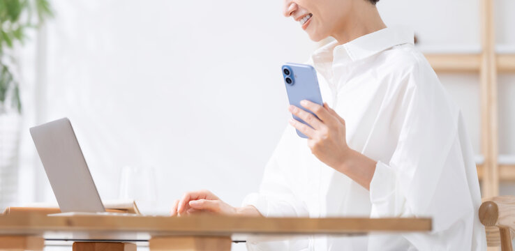 スマートフォンとノートパソコンを使う女性