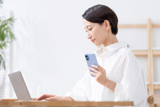 スマートフォンとノートパソコンを使う女性