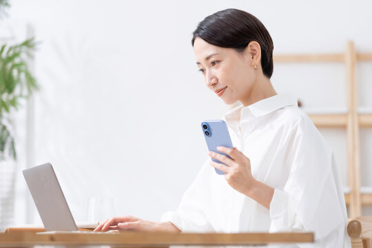 スマートフォンとノートパソコンを使う女性