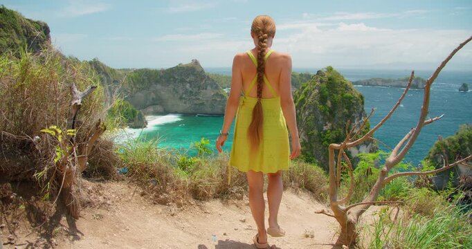 Young woman with long braid enjoys stunning ocean view at Diamond Beach in Nusa Penida Bali