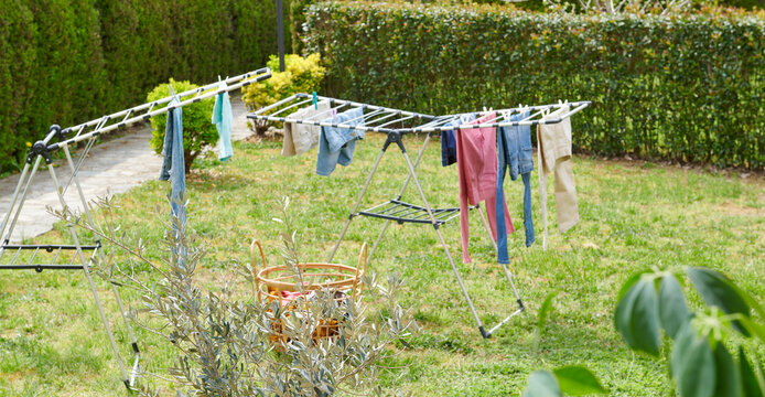 Colorful clothes drying on a outdoor drying rack in a sunny garden, featuring neatly hung garments, sustainable air drying, household laundry routine, eco-friendly lifestyle, fresh clean clothing, spr