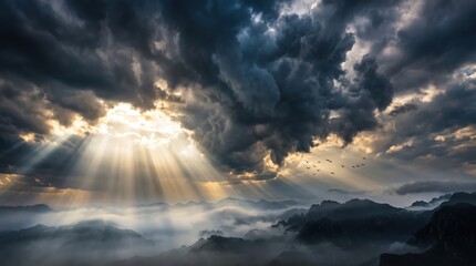 Obraz premium Dramatic mountain landscape with sun rays breaking through storm clouds, fog filled valleys and distant ridgelines with birds in flight, moody atmospheric scene