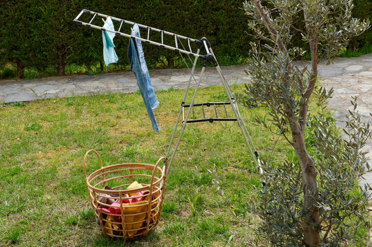 Colorful clothes drying on a outdoor drying rack in a sunny garden, featuring neatly hung garments, sustainable air drying, household laundry routine, eco-friendly lifestyle, fresh clean clothing, spr